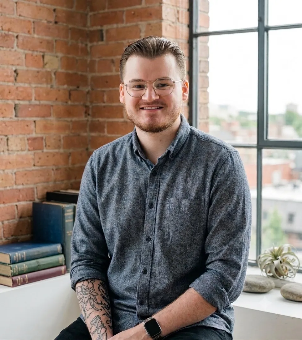 Brandon Moore, seated by a window in front of a brick wall
